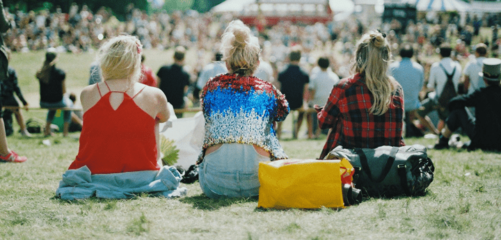 Backs of 3 women sitting on grass