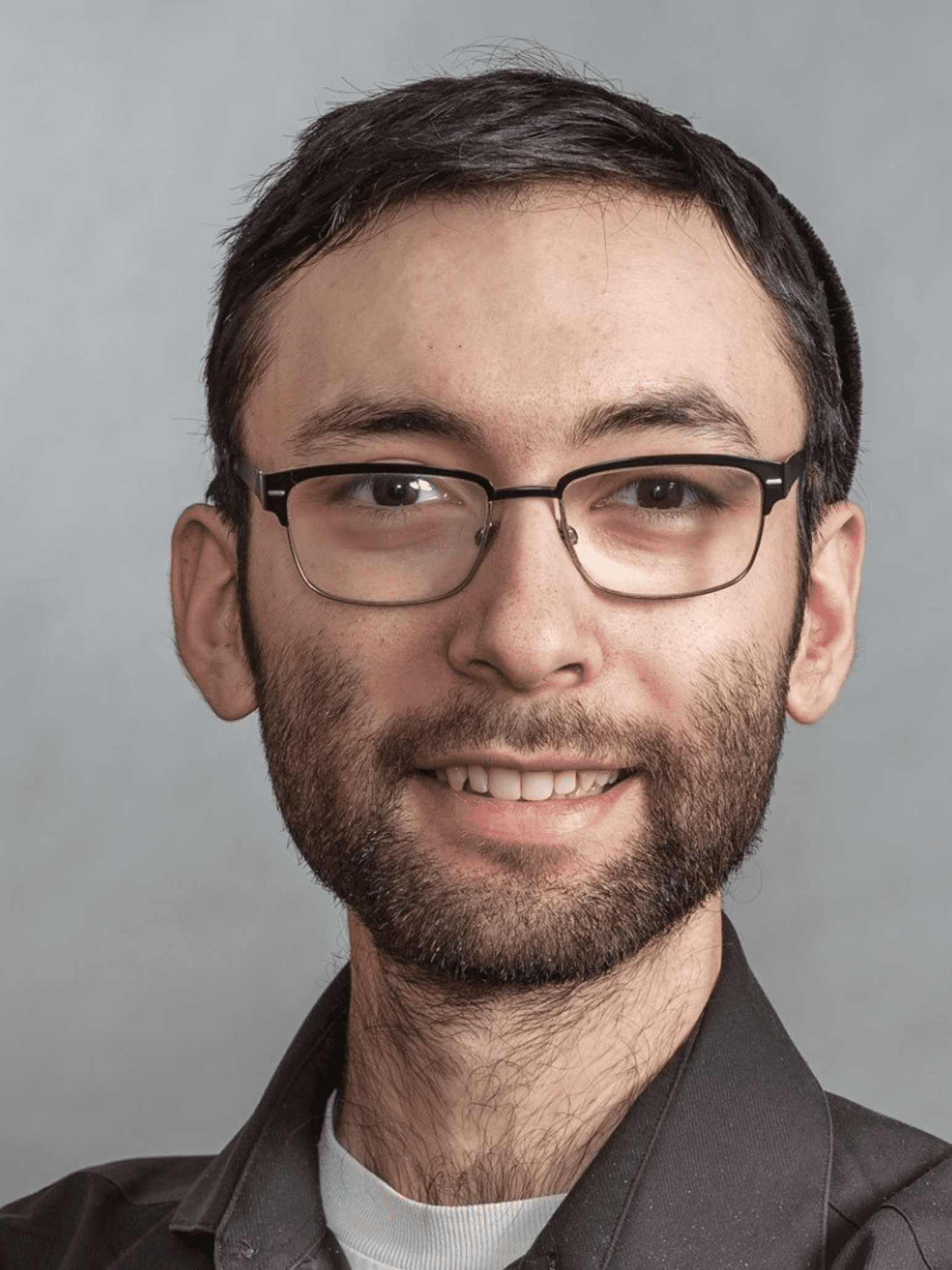 Benjamin Miller's headshot. Benjamin is facing the camera with a smile and wearing spectacles.