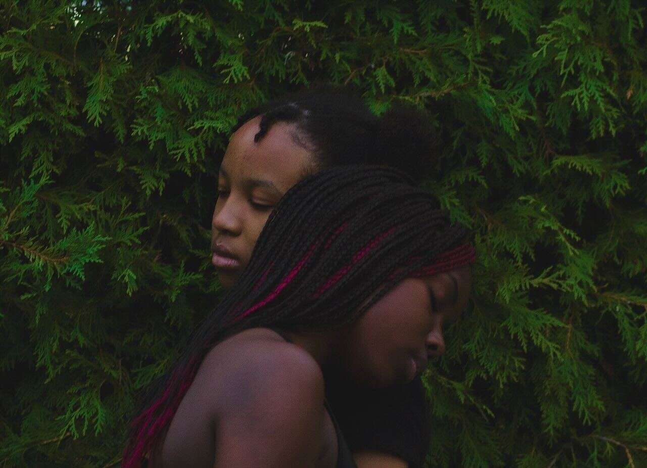 Image of two Black people hugging in nature
